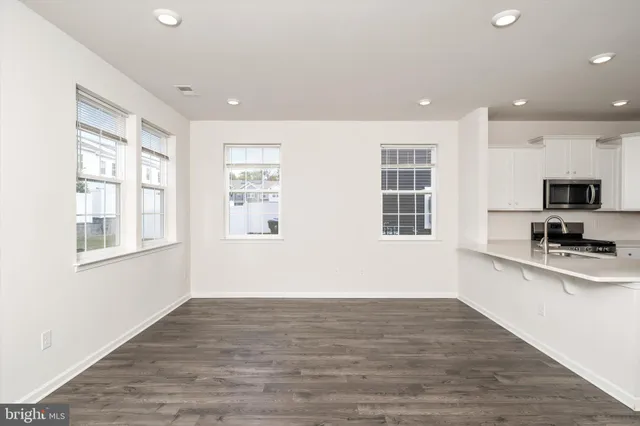 a view of a kitchen with wooden floor and stainless steel appliances