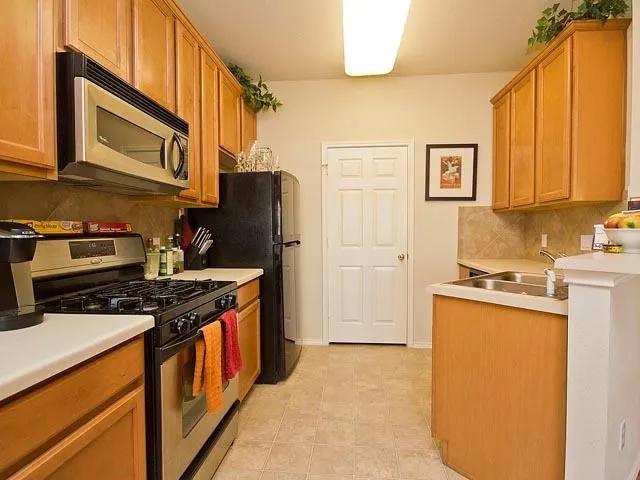 a kitchen with stainless steel appliances granite countertop a stove a refrigerator and a sink