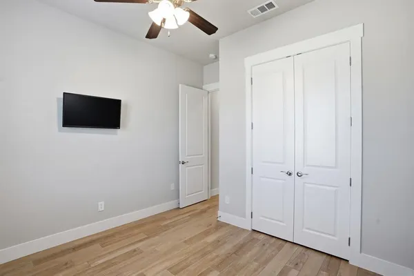 an empty room with wooden floor and mirror on ceiling fan