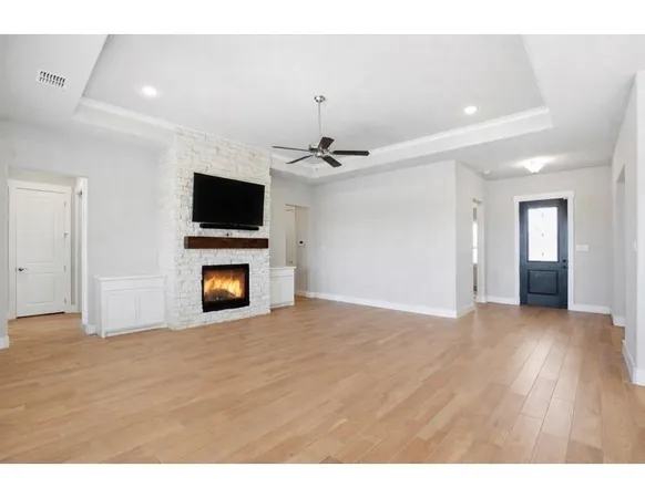 a view of a livingroom with a fireplace a chandelier a ceiling fan and wooden floor
