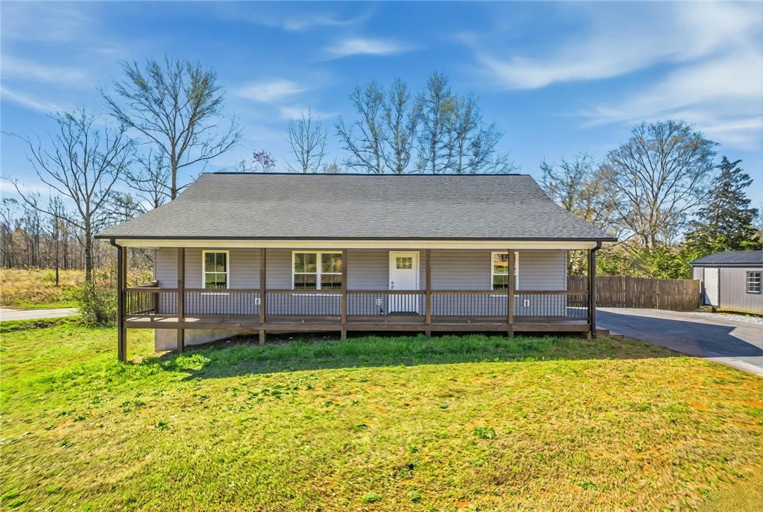 A charming single-story residence with a welcoming covered front porch, nestled on a verdant lot.
