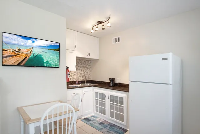 a kitchen with stainless steel appliances granite countertop a refrigerator a stove a sink and a dining table with wooden floor