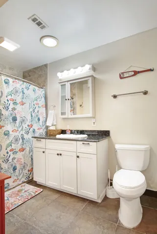 a bathroom with a granite countertop toilet sink and mirror