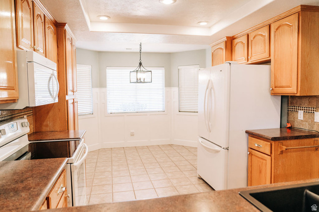1825 West Mathis Park Place, Unit 40 St. George, UT 84770 - Photo 23 of 28 Kitchen featuring white appliances, dark countertops, backsplash, a wainscoted wall, and hanging light fixtures