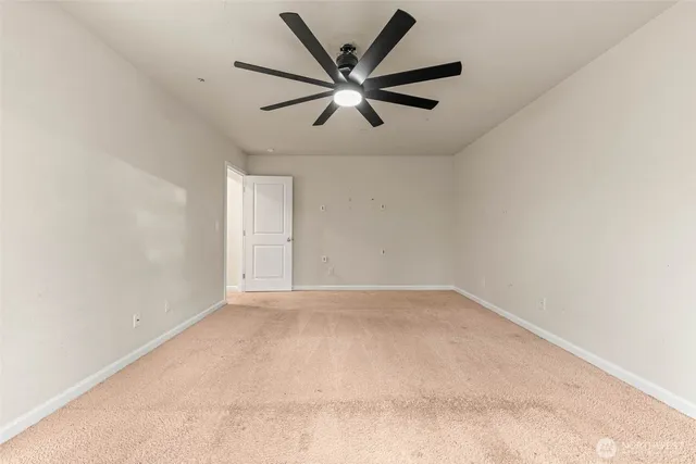 an empty room with ceiling fan and window
