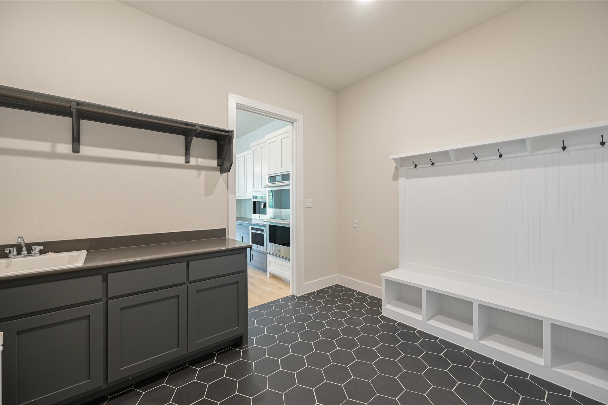 913 Presa Arriba Road Austin, TX 78733 - Photo 12 of 30 A versatile utility area with a sink and storage, featuring a mudroom-style bench with hooks.