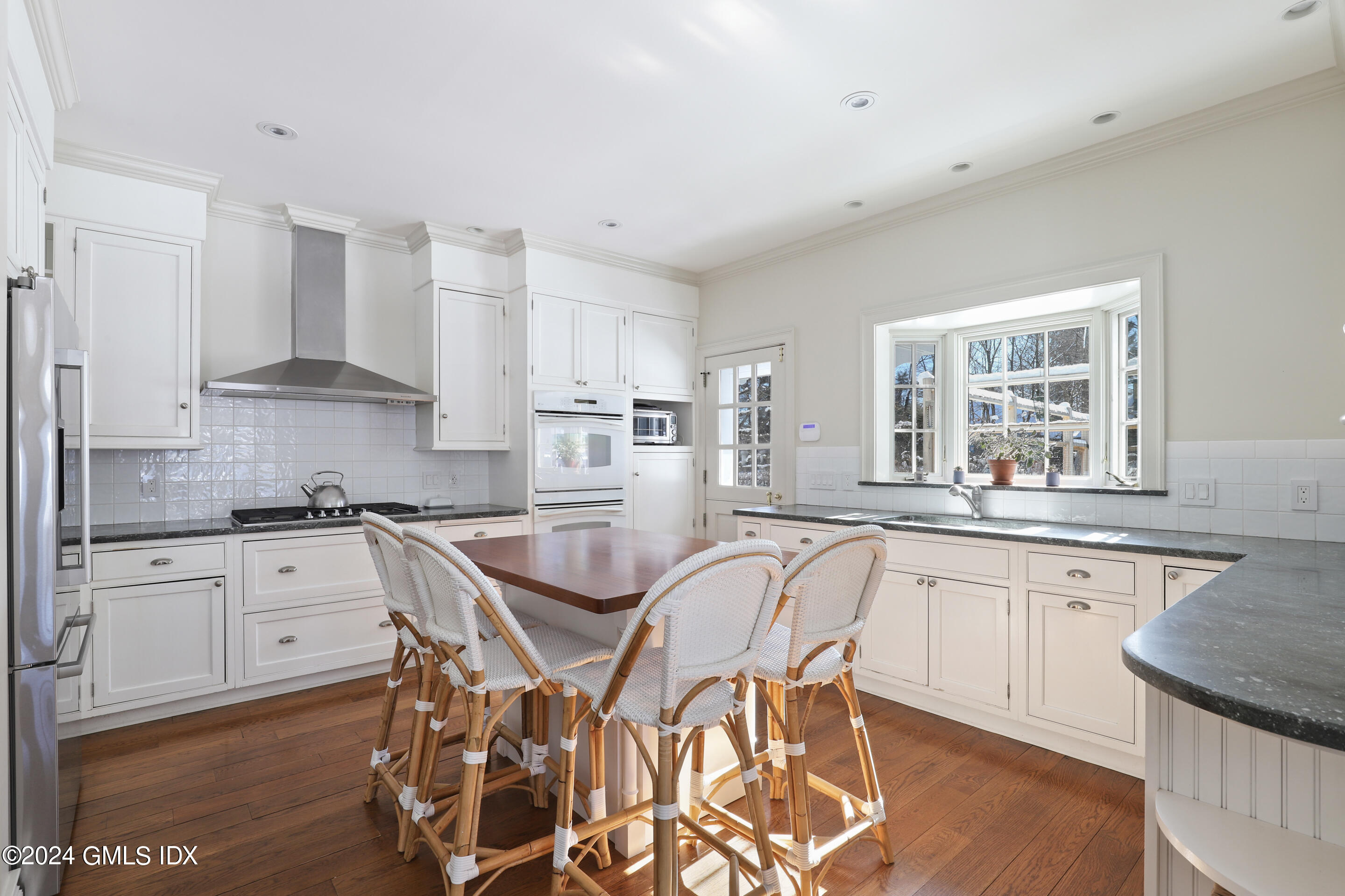 Undisclosed Address Greenwich, CT 06830 - Photo 6 of 19 a kitchen with granite countertop white cabinets a sink a stove a dining table and chairs