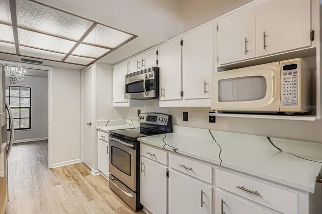 a kitchen with granite countertop white cabinets and stainless steel appliances