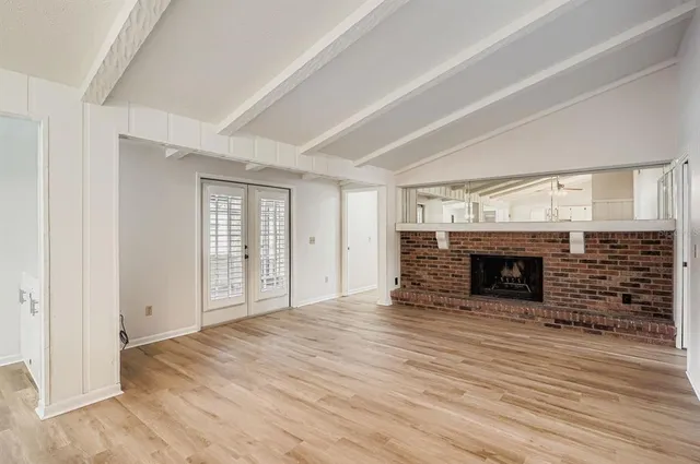 an empty room with wooden floor fireplace and windows