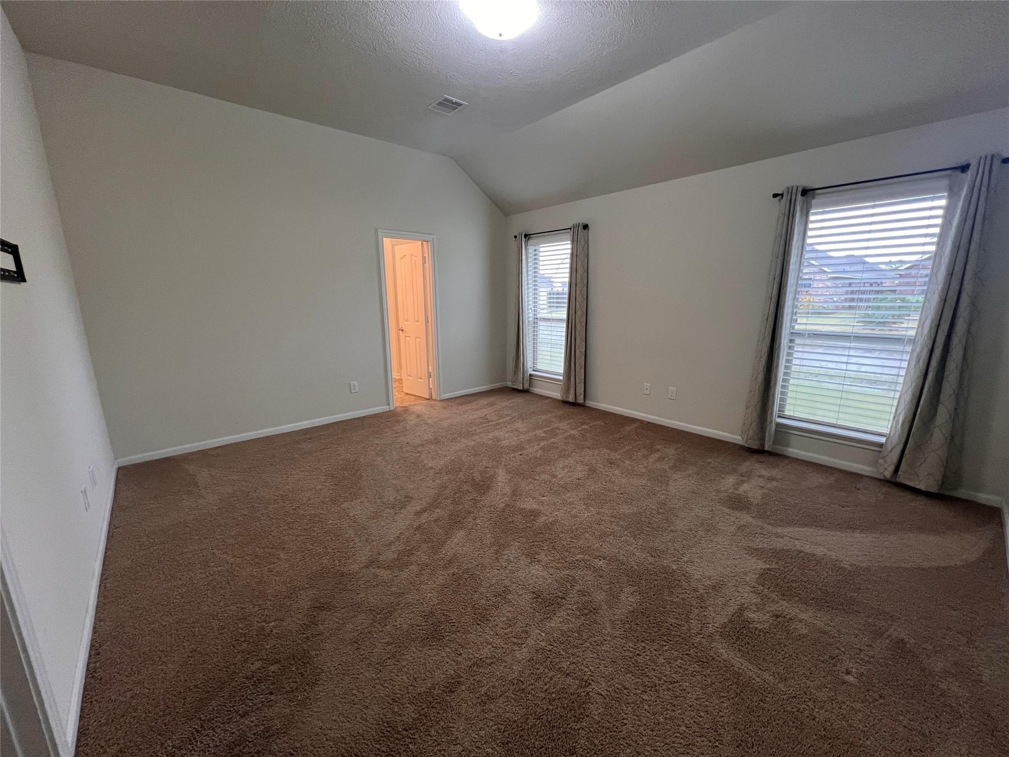 2502 Redrock Road League City, TX 77573 - Photo 7 of 19 The primary bedroom boasts stunning floor-to-ceiling windows that flood the space with natural light, complemented by elegant turtleback ceilings that add a touch of architectural charm.