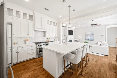 a large white kitchen with a white countertops a stove and a fireplace with wooden floor