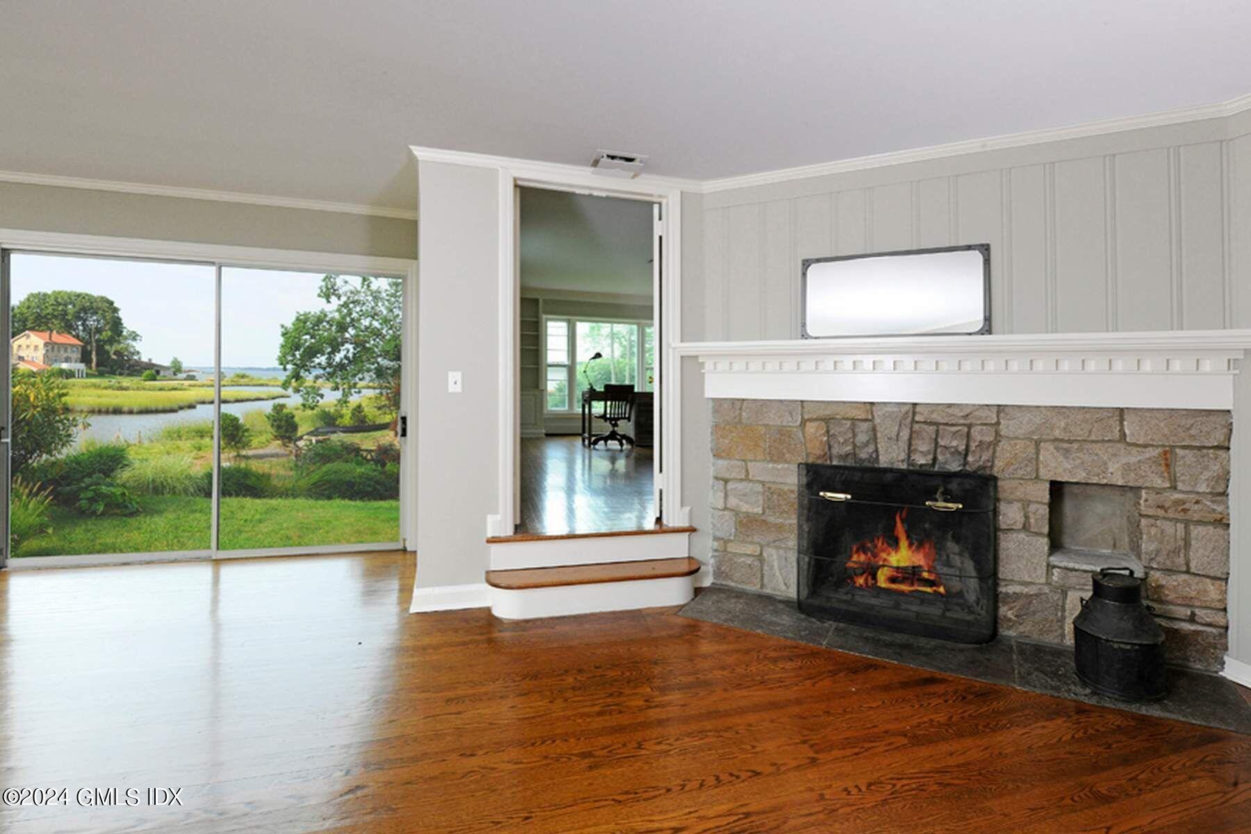 8 Indian Point Lane Riverside, CT 06878 - Photo 6 of 18 a living room with a fireplace and a floor to ceiling window