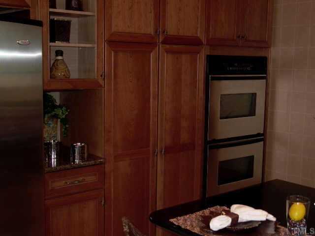 3915 Morvan Way Raleigh, NC 27612 - Photo 4 of 12 Chef's kitchen boasts cherry cabinets, SS appliances, deep ceramic sink, ceramic tile flooring - open to the brkfst area & view into the family and dining room. Home audio system is to the right of double oven.