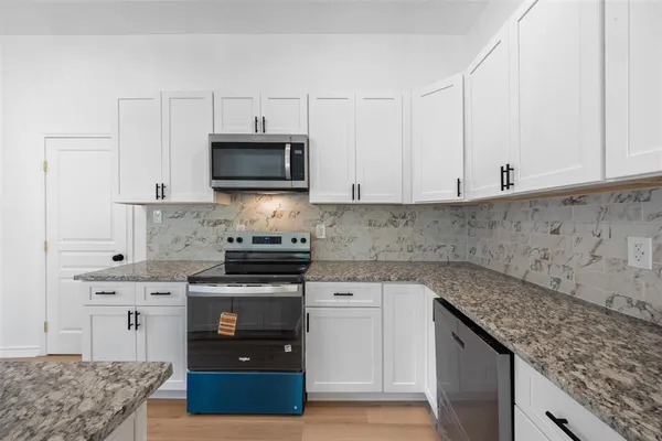 a kitchen with stainless steel appliances granite countertop a stove a sink and a microwave