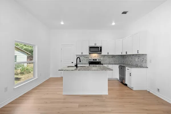 a large kitchen with a center island and stainless steel appliances