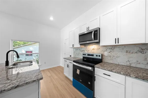 a kitchen with granite countertop a sink a stove and microwave