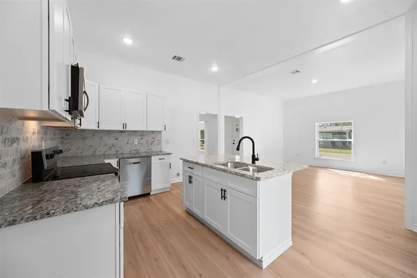 a large kitchen with stainless steel appliances granite countertop a sink stove and wooden floor