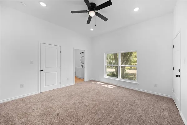an empty room with a ceiling fan and window