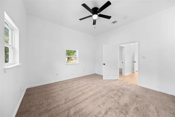 an empty room with a ceiling fan and window