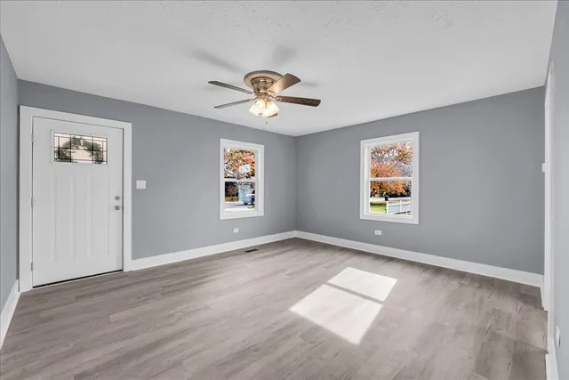 an empty room with windows and fan