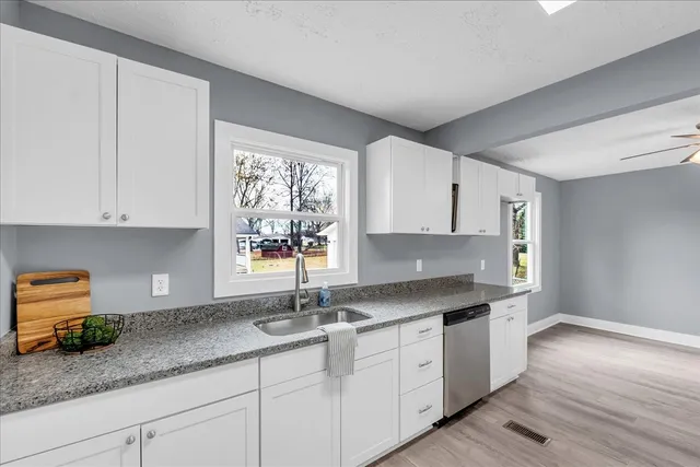 a kitchen with granite countertop a sink stainless steel appliances and cabinets