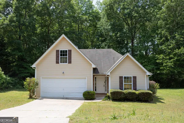 a view of a house with a yard and large tree