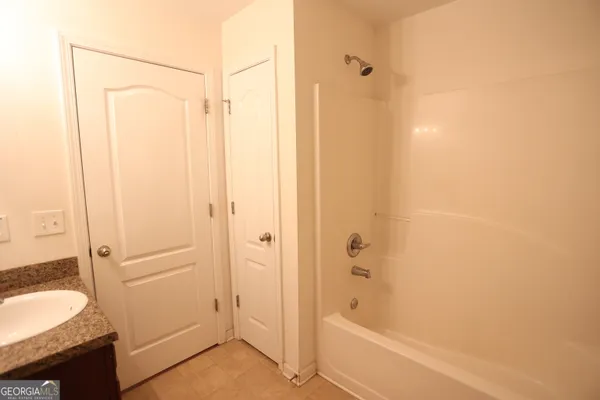 a bathroom with a granite countertop tub shower sink vanity and a sink