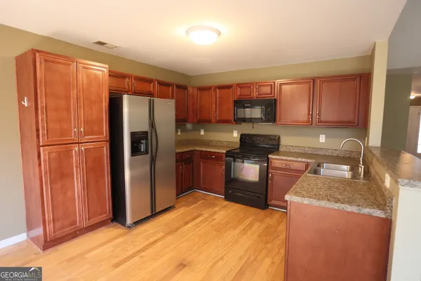 a kitchen with granite countertop stainless steel appliances a refrigerator and a sink