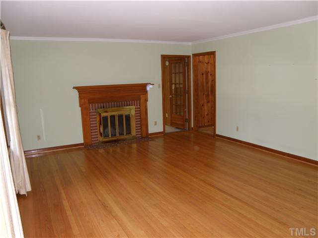 5121 Wickham Road Raleigh, NC 27606 - Photo 3 of 21 an empty room with wooden floor fireplace and windows