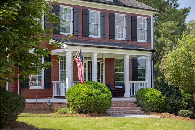 a view of a brick building with many windows plants and large trees