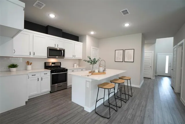 a kitchen with stainless steel appliances a white table chairs and a refrigerator