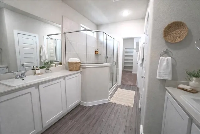 a bathroom with a double vanity sink a mirror and a shower