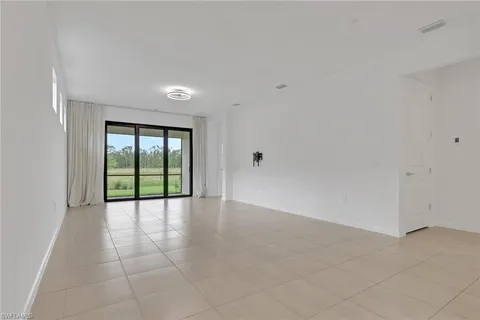 an empty room with windows and chandelier fan