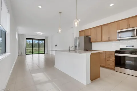 a kitchen with stainless steel appliances granite countertop a stove a sink and a refrigerator with wooden floor