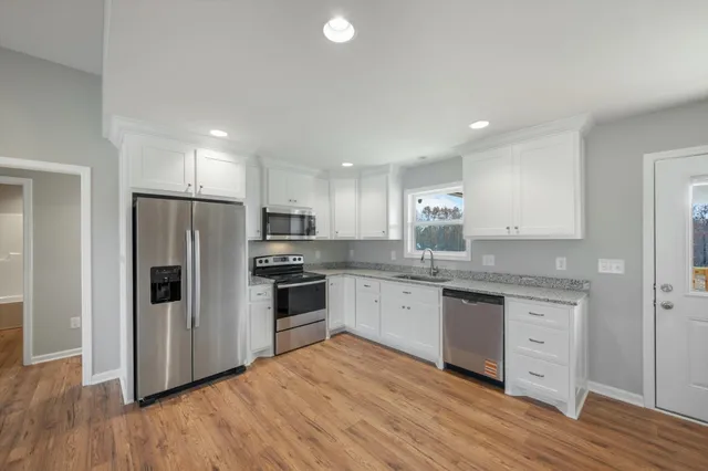 a kitchen with granite countertop a refrigerator stove top oven and sink