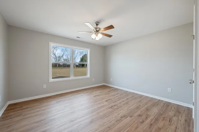 a view of an empty room with wooden floor and a window