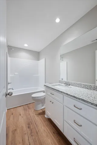 a bathroom with a granite countertop sink a toilet and bathtub