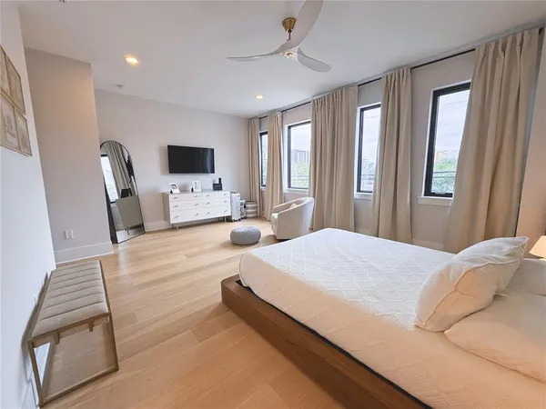 a bedroom with a bed wooden floor and flat screen tv