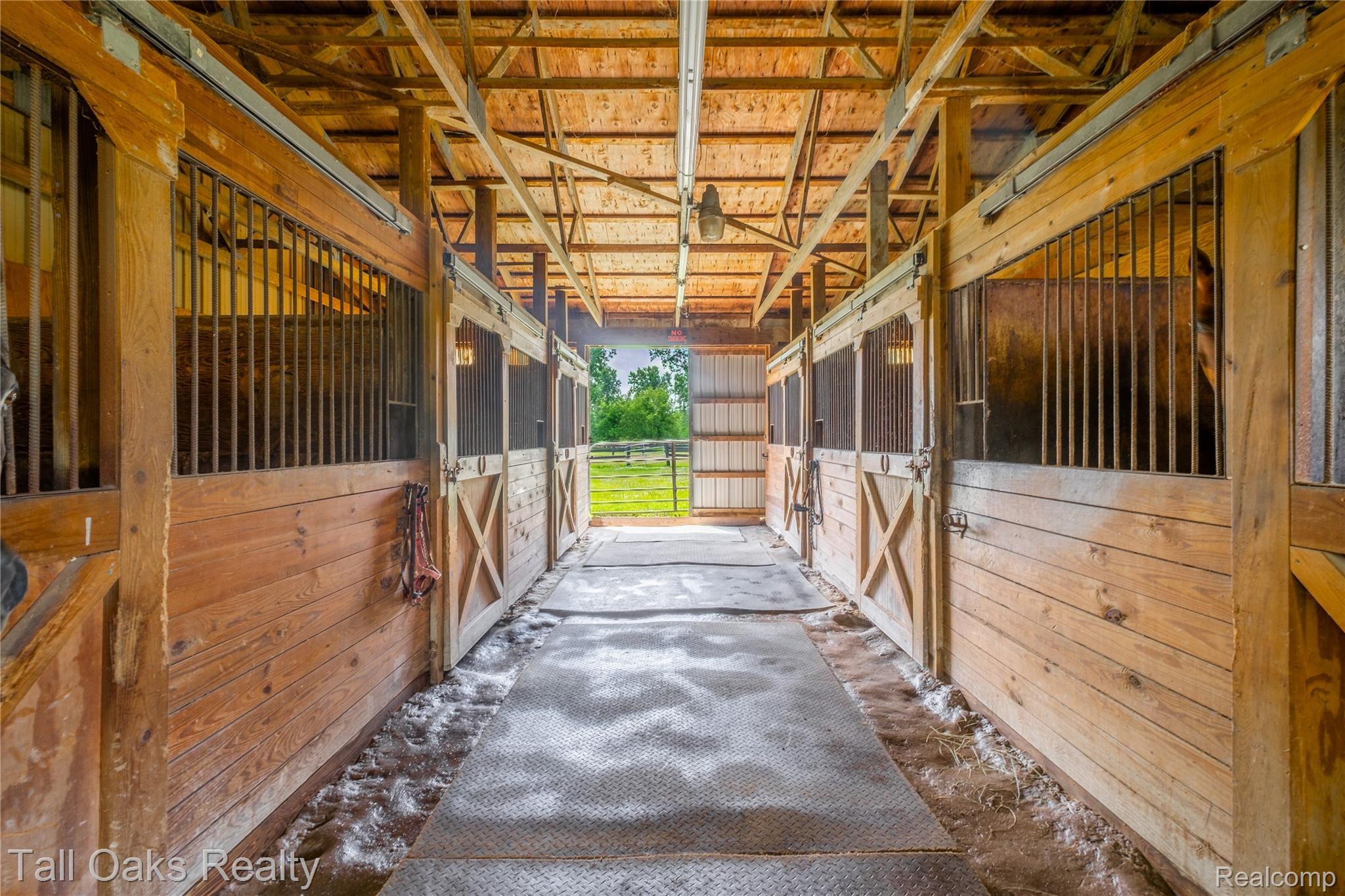 79330 Capac Road Armada, MI 48005 - Photo 11 of 42 Wood-paneled stable featuring multiple stalls with metal grates