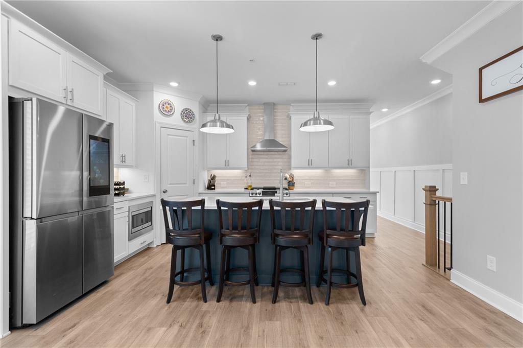 300 Olmstead Way Alpharetta, GA 30022 - Photo 11 of 52 a kitchen with kitchen island granite countertop a dining table chairs refrigerator and wooden floor