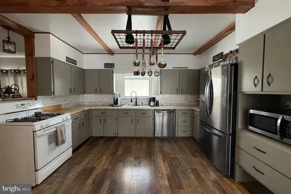 a kitchen with a chandelier stainless steel appliances a sink and cabinets