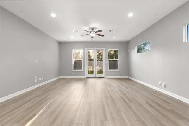 an empty room with wooden floor and windows