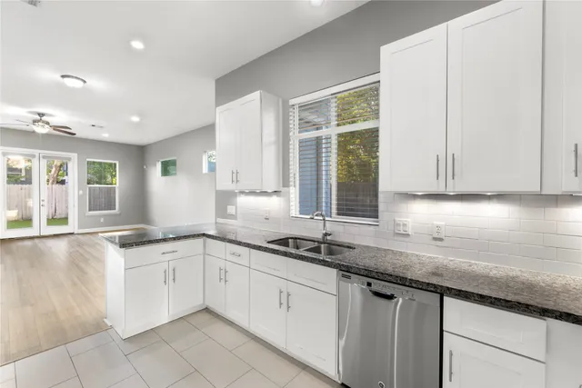a white kitchen with granite countertop a sink and white cabinets