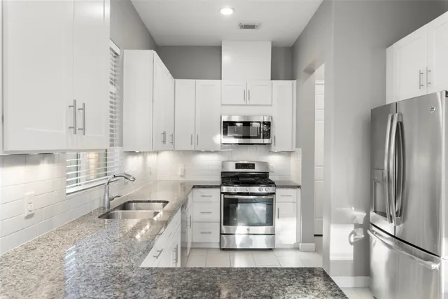 a kitchen with stainless steel appliances granite countertop a refrigerator sink and stove