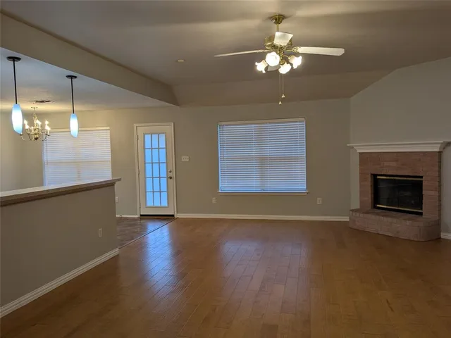 a view of an empty room with a fireplace and a chandelier fan