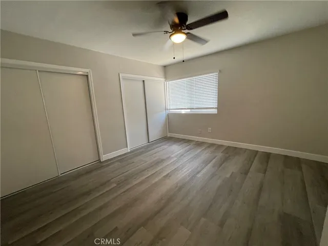 an empty room with wooden floor fan and windows