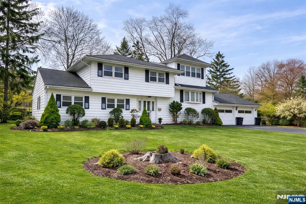 a front view of a house with a garden and trees