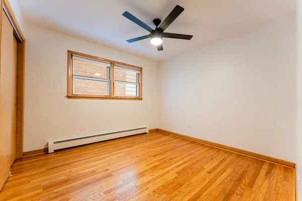 an empty room with wooden floor and ceiling fan