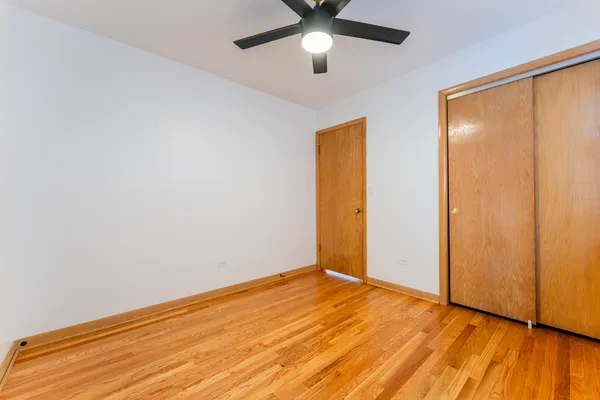 an empty room with wooden floor and a ceiling fan