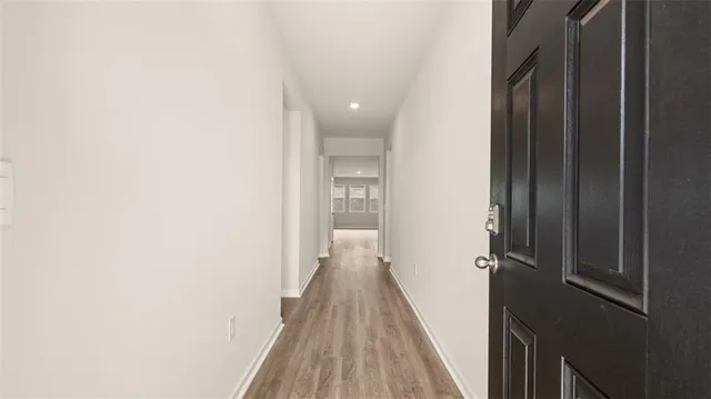 a view of a hallway with wooden floor and a bathroom